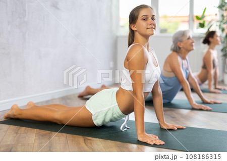 Teenage girl doing yoga in group in studio 108186315