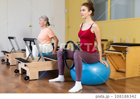 Active women perform exercises with fitness balls and Pilates rings Active women perform exercises with fitness balls and Pilates rings 108186342