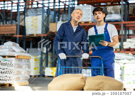 Guy check papers invoices with elderly male employee and revise availability of goods in stock Guy check papers invoices with elderly male employee and revise availability of goods in stock 108187087