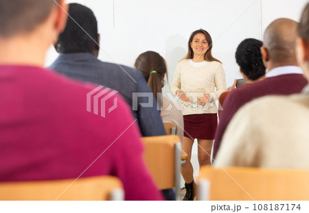 Group of students attentively listening to lecture of female teacher Group of students attentively listening to lecture of female teacher 108187174