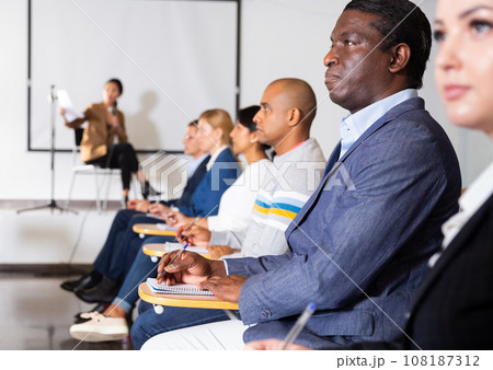 Focused African American listening to lecture at conference 108187312