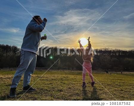 happy man with little girl playing with soap bubbles happy man with little girl playing with soap bubbles 108187582