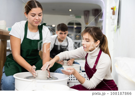 Two young women sculpt product on potter's wheel Two young women sculpt product on potter's wheel 108187866