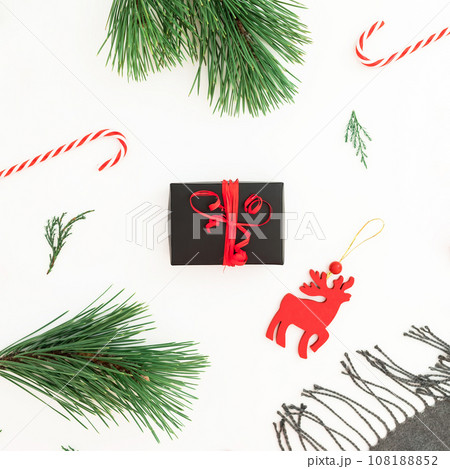 Christmas toy, scarf, pine branches, candy canes and gift box on white background. Flat lay 108188852