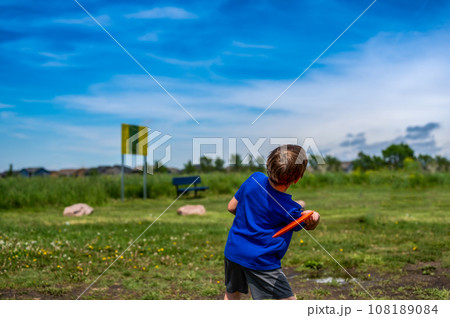 Caucasian child playing disc golf and making the first toss Caucasian child playing disc golf and making the first toss 108189084