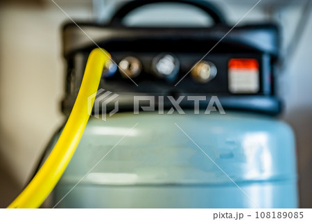 Selective focus on a hose connected to a Pancake air compressor sitting on a shelf Selective focus on a hose connected to a Pancake air compressor sitting on a shelf 108189085