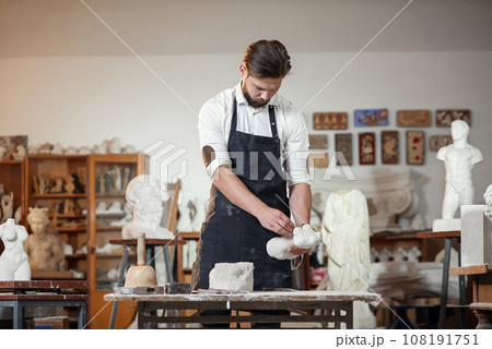 Bearded sculptor measures stone woman torso to make copy of it from limestone at creative studio. Bearded sculptor measures stone woman torso to make copy of it from limestone at creative studio. 108191751