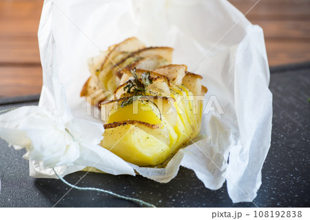 Baked potatoes stuffed with lard in baking paper. 108192838