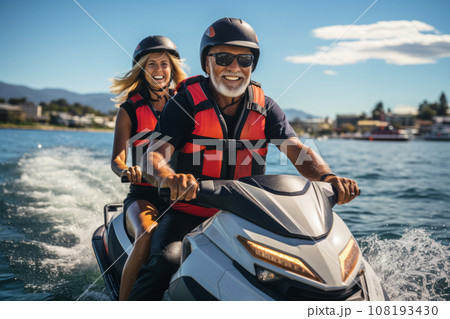 Elderly happy couple having fun on jet ski during beach island tour - Active seniors and world travel concept with seniors riding on jet ski - Warm vintage vibrant filter 108193430