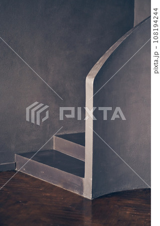 A modern black curved staircase indoors, a staircase made of black stone, a symbol of modern life. With space to copy. High quality photo 108194244