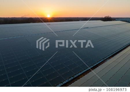 Aerial view of solar power plant with blue photovoltaic panels mounted on industrial building roof for producing green ecological electricity. Production of sustainable energy concept 108196973