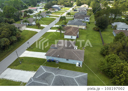 Aerial view of small town America suburban landscape with private homes between green palm trees in Florida quiet residential area Aerial view of small town America suburban landscape with private homes between green palm trees in Florida quiet residential area 108197002