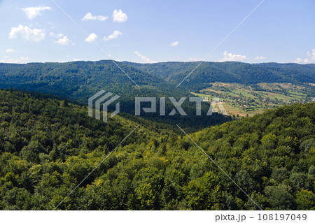 Aerial view of mountain hills covered with dense green lush woods on bright summer day. Aerial view of mountain hills covered with dense green lush woods on bright summer day. 108197049