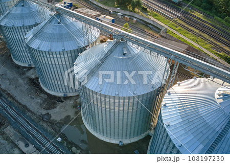Aerial view of industrial ventilated silos for long term storage of grain and oilseed. Metal elevator for wheat drying in agricultural zone Aerial view of industrial ventilated silos for long term storage of grain and oilseed. Metal elevator for wheat drying in agricultural zone 108197230