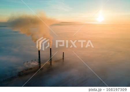 Aerial view of coal power plant high pipes with black smoke moving up polluting atmosphere at sunset. 108197309
