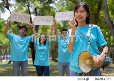 Happy young Asian students diverse volunteers hold a campaign sign for cleaning in the park, The concept of environmental conservation on world environment day, recycling, charity for sustainability. 108203121