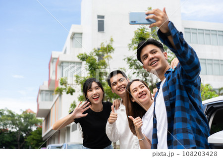 Group of happy young Asian students selfies and videos with smartphones together for vlog and social media on summer vacation. Concept of tourism and travel and road trip, friendship lifestyle. 108203428