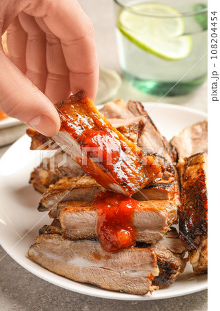 Woman with grilled ribs at light grey table, closeup 108204454