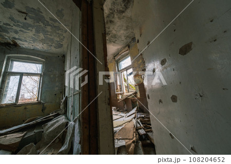 From above interior of shabby abandoned room with peeling painted walls wooden column supporting beam while rubbish garbage of destroyed rubble and furniture on dirty floor with windows in daylight From above interior of shabby abandoned room with peeling painted walls wooden column supporting beam while rubbish garbage of destroyed rubble and furniture on dirty floor with windows in daylight 108204652