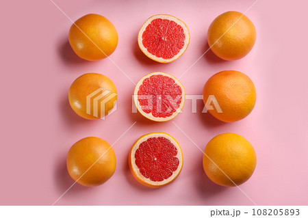 Cut and whole ripe grapefruits on pink background, flat lay 108205893