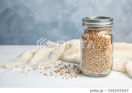 Jar with green buckwheat on white table. Space for text 108205897