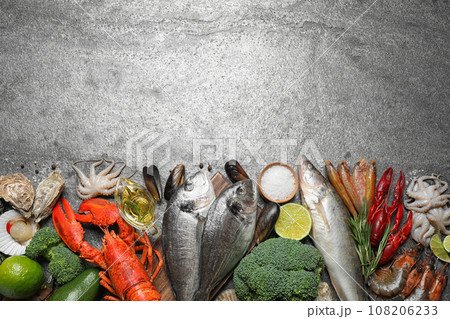 Fresh fish and different seafood on grey table, flat lay. Space for text Fresh fish and different seafood on grey table, flat lay. Space for text 108206233