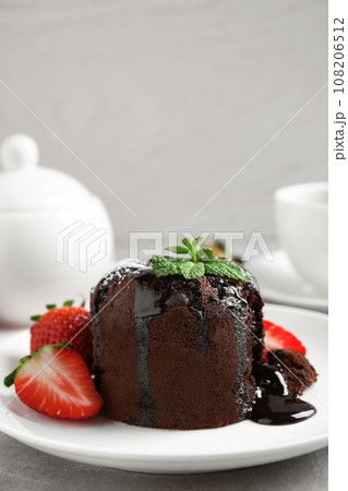 Delicious warm chocolate lava cake with mint and strawberries on table. Space for text 108206512