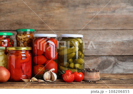Glass jars with different pickled vegetables on wooden table 108206855