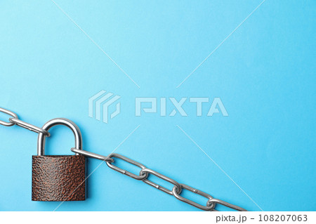 Steel padlock, chain and space for text on light blue background, top view. Safety concept 108207063