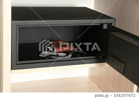 Open steel safe with wallet, watch and smartphone in wooden closet at hotel 108207072