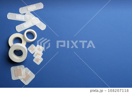 Different types of sticking plasters on blue background, flat lay. Space for text 108207118