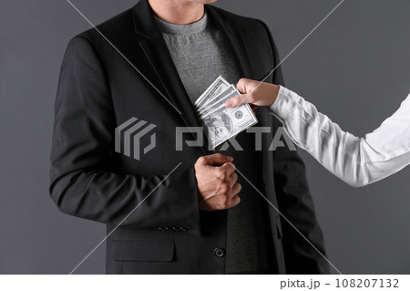 Woman giving bribe money to man on dark background, closeup Woman giving bribe money to man on dark background, closeup 108207132