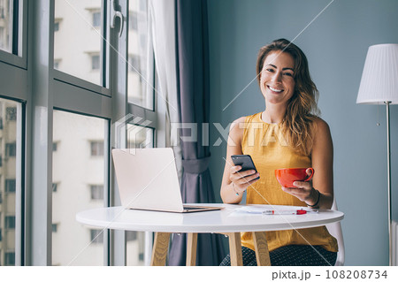 Happy woman resting and using smartphone at home Happy woman resting and using smartphone at home 108208734