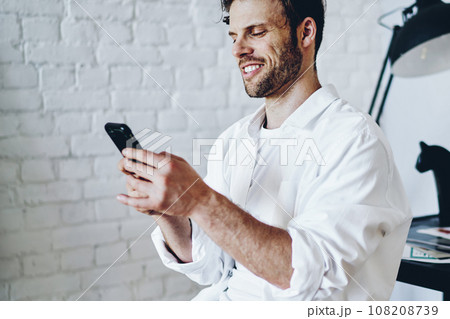Cheerful caucasian man satisfied with tariffs for 4G internet connection on mobile phone Cheerful caucasian man satisfied with tariffs for 4G internet connection on mobile phone 108208739