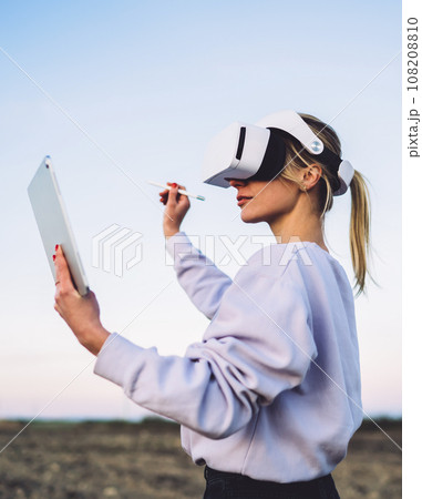 Woman in VR headset using touchpad and stylus for virtual reality 108208810