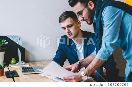 Young man showing papers to colleague 108209262