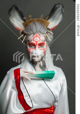 Actress woman with animal makeup, mask and stage asian costume posing on black background. Actress woman with animal makeup, mask and stage asian costume posing on black background. 108209302