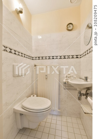 a white bathroom with black and white tiles on the walls, toilet, sink, and mirror in the corner 108209475