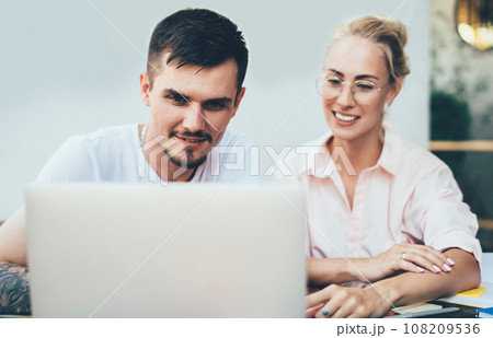 Cheerful man and woman coworking on computer Cheerful man and woman coworking on computer 108209536