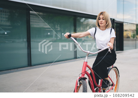Attractive adult cyclist female riding bicycle in city 108209542
