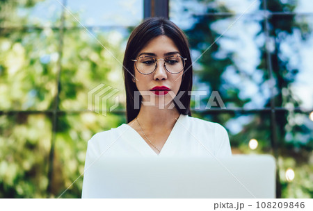 Young Spanish student in optical glasses making online research of digital Young Spanish student in optical glasses making online research of digital 108209846