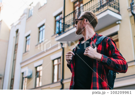 Pensive man looking back and contemplating while standing on street in sunny summer day Pensive man looking back and contemplating while standing on street in sunny summer day 108209961