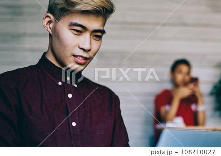 Serious Asian man browsing laptop in workspace Serious Asian man browsing laptop in workspace 108210027