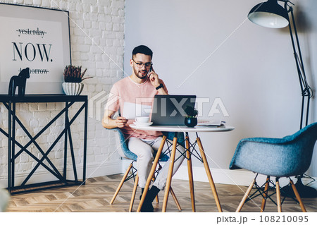 caucasian male freelancer calling on cellphone at home 108210095