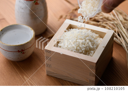 枡に盛ったお米と日本酒の熱燗 ( 白米 )稲穂 木目バック 枡に盛ったお米と日本酒の熱燗 ( 白米 )稲穂 木目バック 108210105