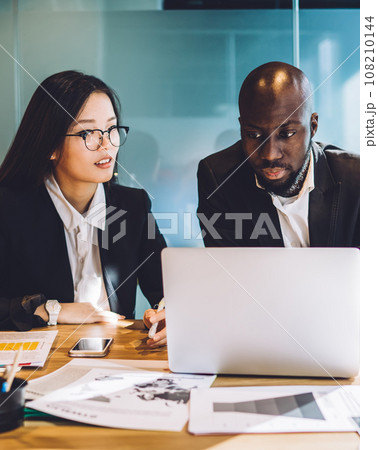 Multiethnic business partners working on project together with laptop at conference room 108210144