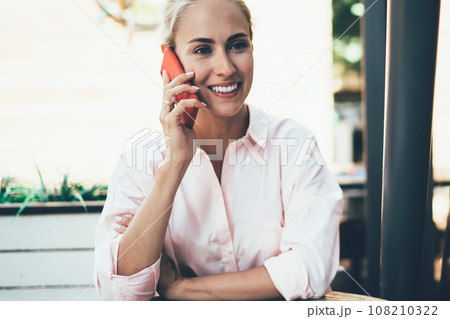 Happy woman talking on phone on cafe terrace 108210322