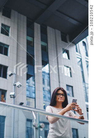 hipster girl using internet connection in roaming on cellphone looking at camera on street 108210542