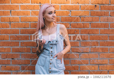 Trendy woman with smartphone looking away Trendy woman with smartphone looking away 108211070