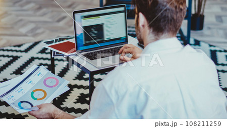 young millennial man browse web page on netbook sitting in living room in modern apartment young millennial man browse web page on netbook sitting in living room in modern apartment 108211259